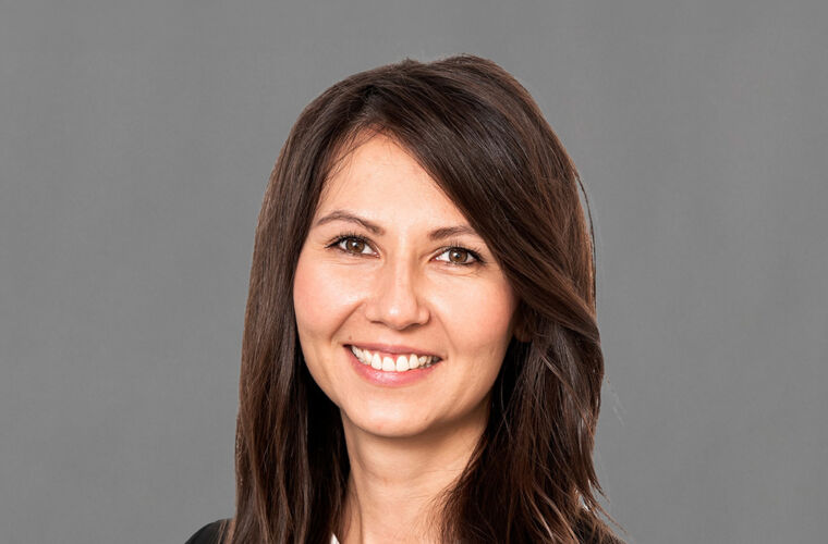 Alibekova Meruyert lächelt und blickt mit leicht geneigtem Kopf in die Kamera.