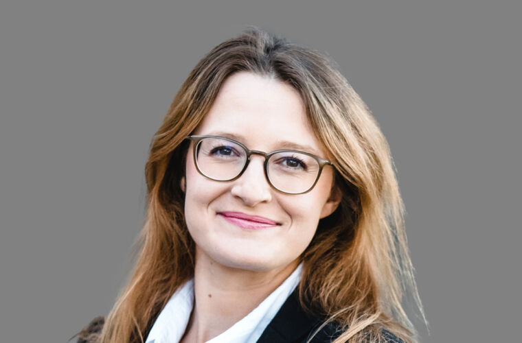 Johanna Vasconcelos Alves, mit offenen Haaren und Brille, in die Kamera lächeln.